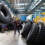 An Indian employee uses a crane to move a tyre at the JK Tyre and Industries Limited  OTR (Off The Road) manufacturing plant in Mysore on August 23, 2016. (Photo by Manjunath KIRAN / AFP) (Photo by MANJUNATH KIRAN/AFP via Getty Images)